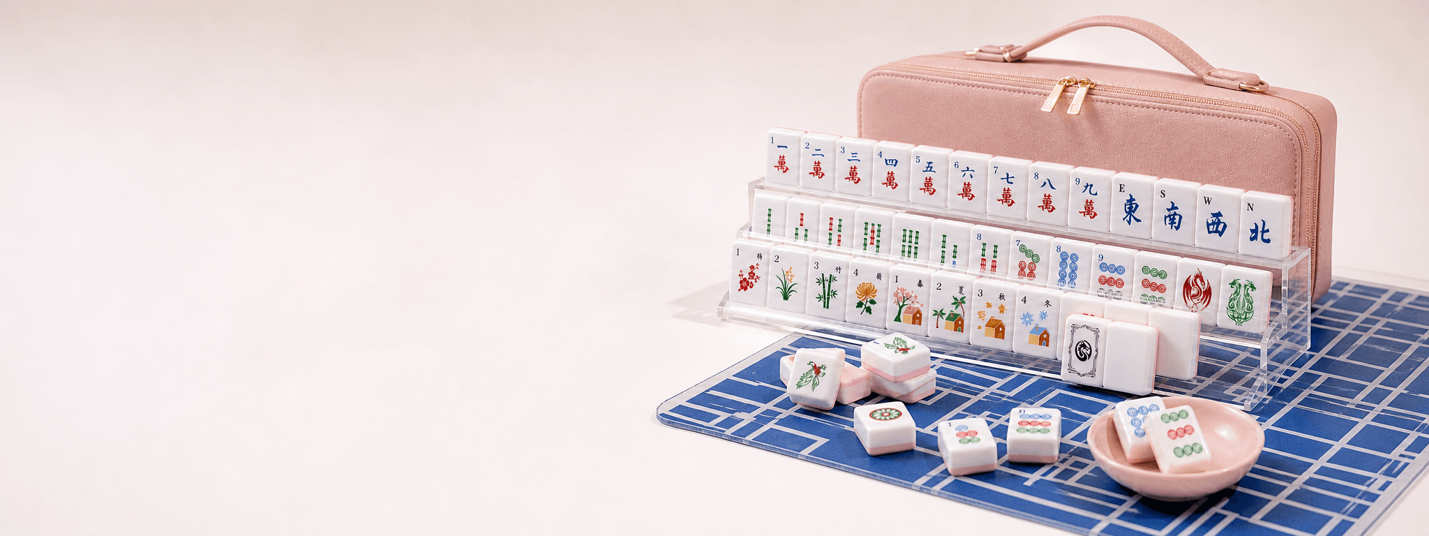 Pink Mahjong case, blue playing mat, and clear acrylic tile racks in a bright gift setting